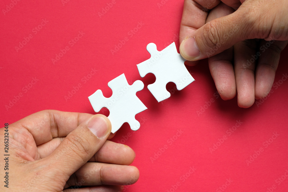 Partnership concept with hands putting puzzle pieces together on red background Partnership concept with hands putting puzzle pieces together on red background