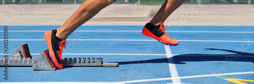 Canvastavla Track spikes shoes feet on starting blocks on running track and field stadium blue lanes