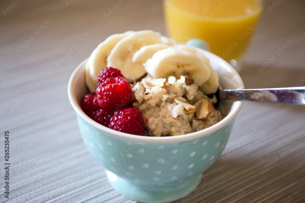 Bowl of homemade oatmeal porridge with banana, raspberry and almonds Bowl of homemade oatmeal porridge with banana, raspberry and almonds