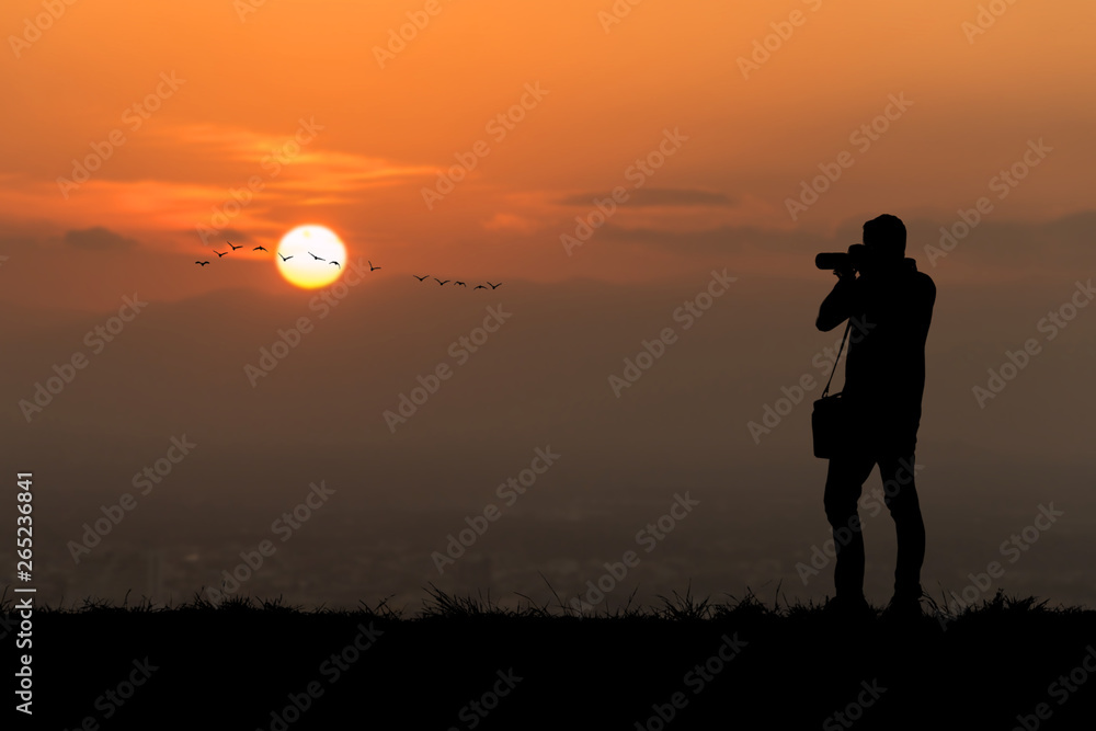 Silhouette photographer on sunset background.