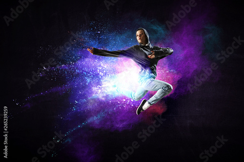 Modern female dancer jumping in hoodie with colourful splashes background. Mixed media © Sergey Nivens