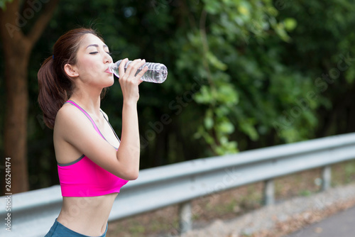 Young asian woman relaxing in the park, Holding water bottle in hand.