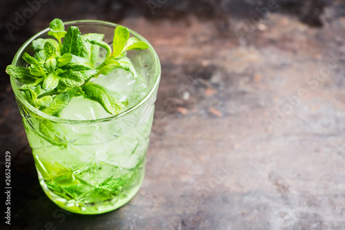 Summer old fashioned beverage with melon liqueur and mint leaves. Selective focus. Shallow depth of field.