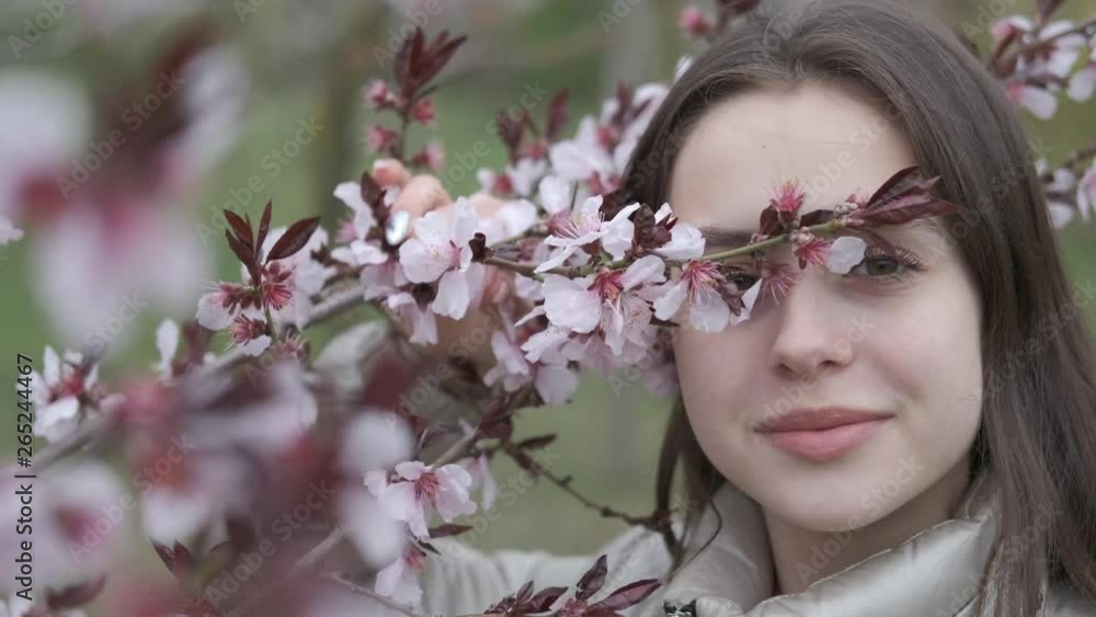 Portrait of a beautiful girl with a flowering tree. A charming girl hides her eyes behind a branch of a blossoming tree. Portrait of a beautiful girl with a flowering tree. A charming girl hides her eyes behind a branch of a blossoming tree.