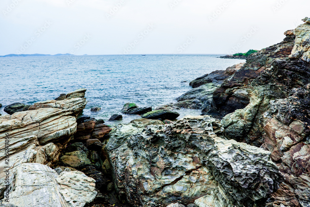 Sea shore and Large stones with blue sky. Dramatic seascape at sunset, Calm atmosphere beside coast of sea, Khao Laem Ya, Rayong Province, Thailand