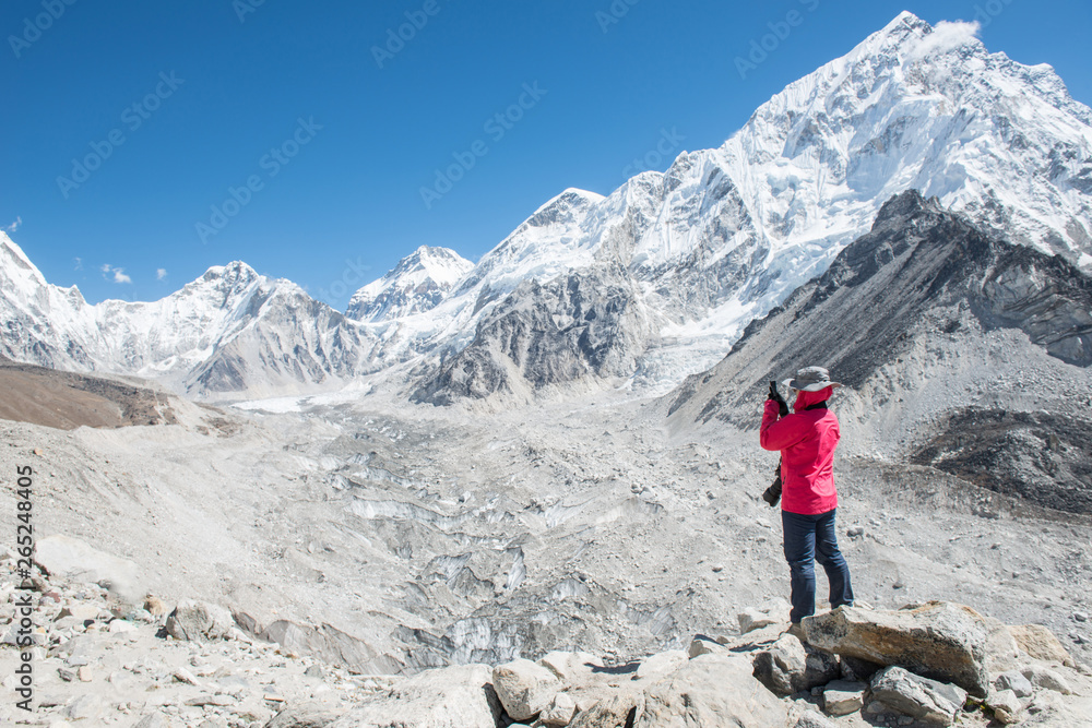 Woman tourist taking photos of beautiful Himalayas mountain range and Khumbu glacier during trekking to Everest base camp in Nepal.