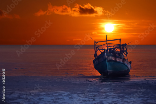 Old broken boat abandoned on the beach at sunset ,Red sky