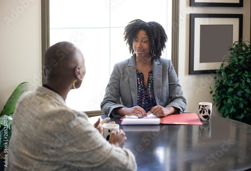 Black African American female businesswomen talking in an office.  The two women looks like a start up co workers or small business partners. photo