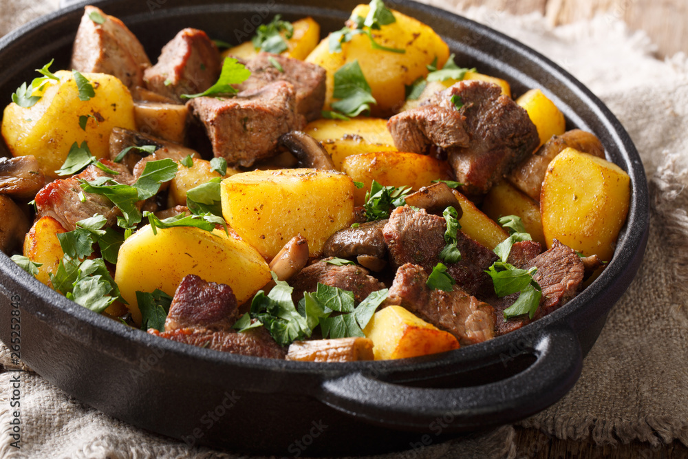 Homemade food of fried pork with potatoes and mushrooms close-up in a frying pan. horizontal Homemade food of fried pork with potatoes and mushrooms close-up in a frying pan. horizontal