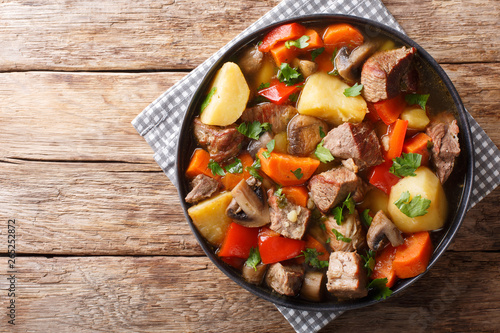 ragout of pork with mushrooms and vegetables close-up on a plate. horizontal top view