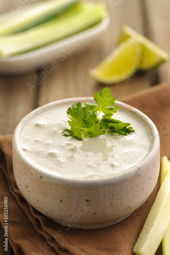 Blue cheese sauce in a portion with fresh vegetables and lime and green parsley. Wooden background and natural napkin. Close up and vertical view.