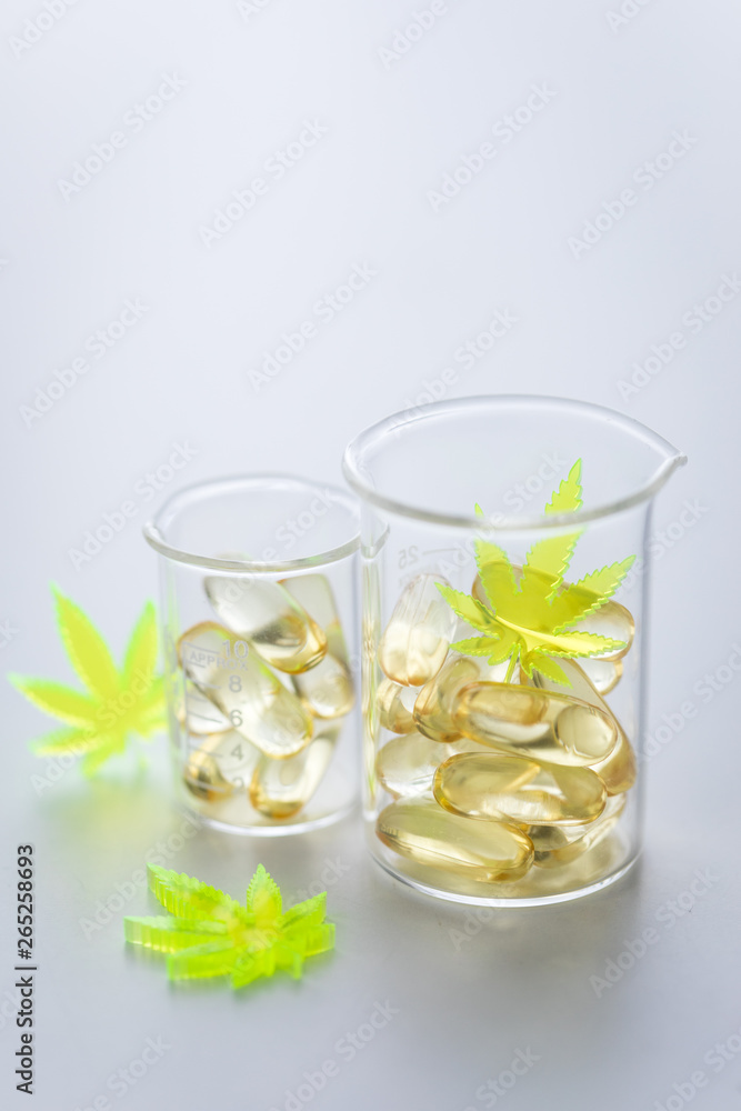 Pillen, Tabletten, Kapseln mit Cannabis Marihuana Hanf und CBD in Labor Becherglas gegen Schmerzen zur Therapie als Medizin 