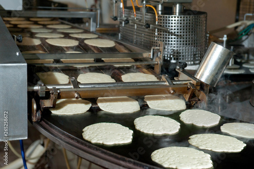 Pancakes are fried on the conveyor in factory