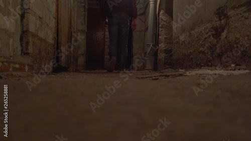 a man walks through a basement, an abandoned building. Scared and runs away, the camera is at ground level. shooting from the side.