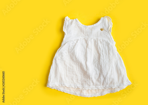 Beautiful cotton muslin vintage baby girl white dress on yellow background - summer