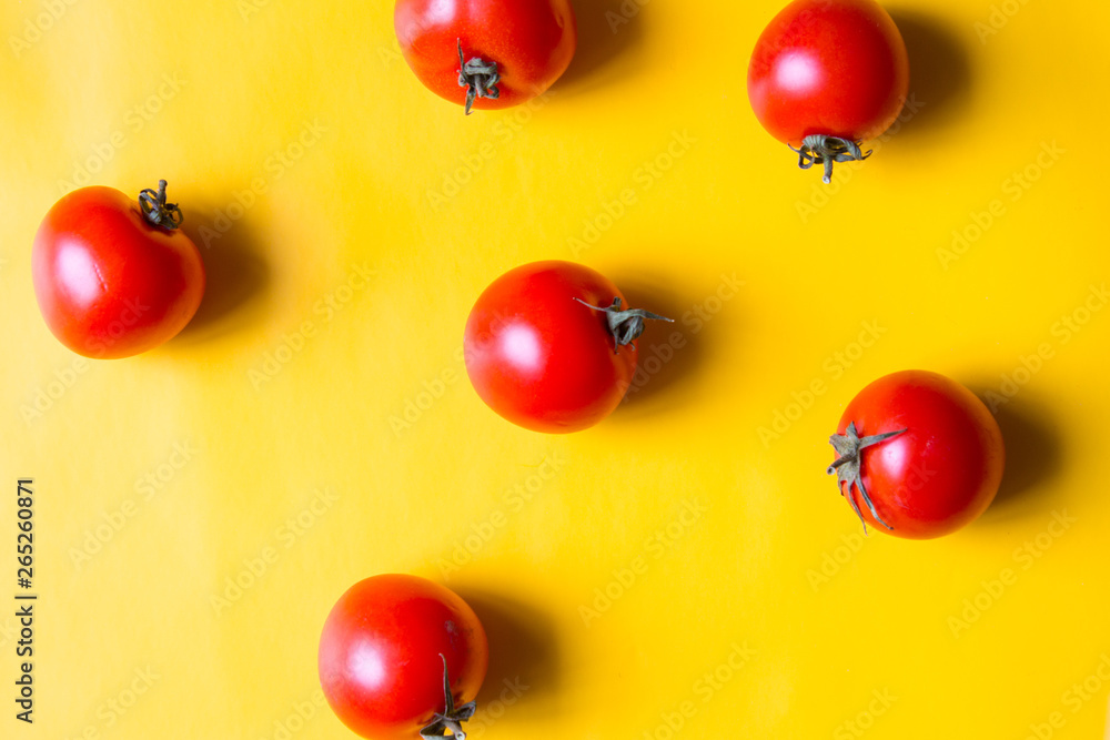 Ripe red tomatoes with green leaves isolated on yellow background. Top view. Ripe red tomatoes with green leaves isolated on yellow background. Top view.