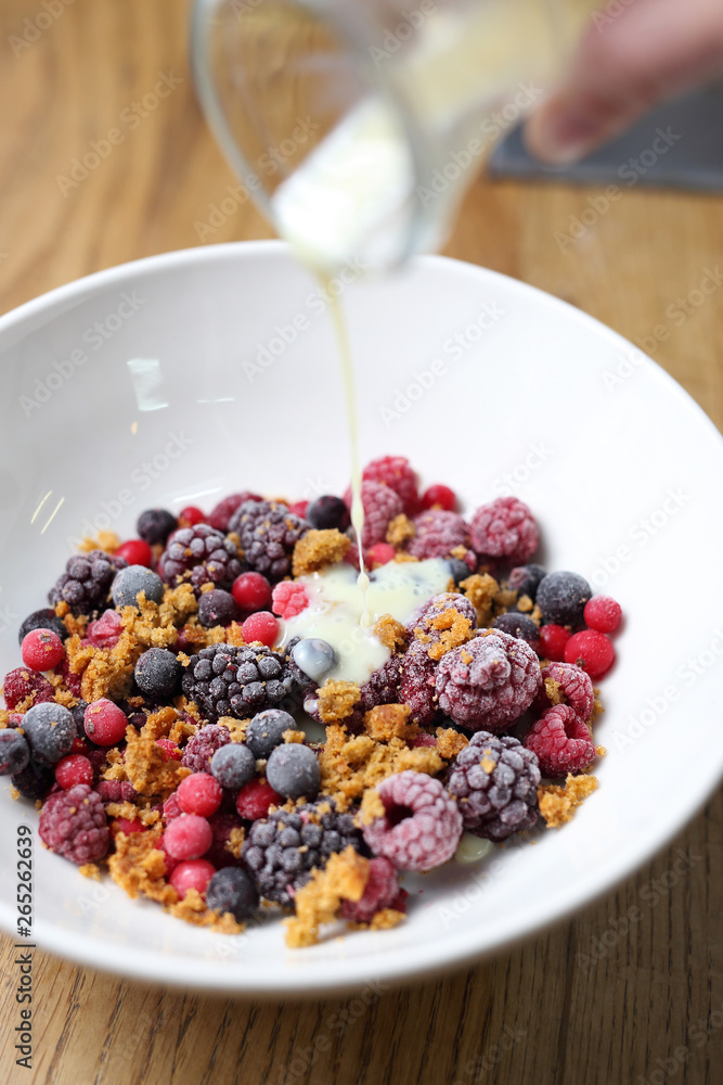 Frozen fruits with granola and yogurt, healthy fruit breakfast.