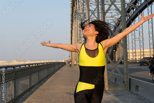 girl running over a bridge at sunset and smiling photo