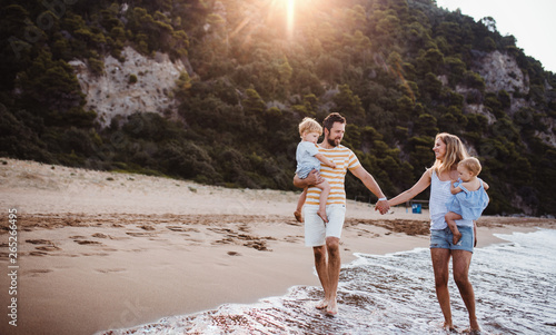 Photography A family with two toddler children walking on beach on summer holiday at sunset