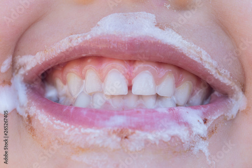 Closeup of young laughing girl eating ice cream with ice cream around her mouth
