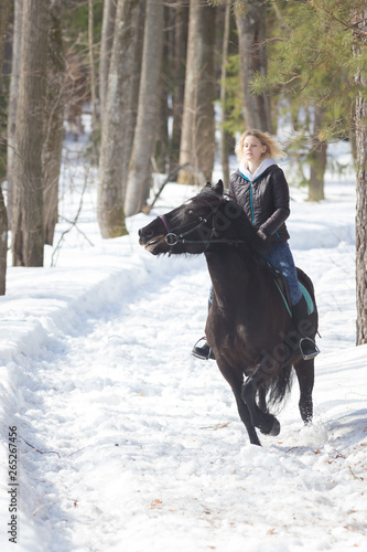 A winter forest. A young woman riding a horse