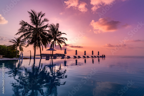 Sunrise blue and pink light scattering across the clouds and pool  reflecting the infinity pool and silhouetted palm trees. Luxury resort and travel destination concept  vacation mood  summer holiday