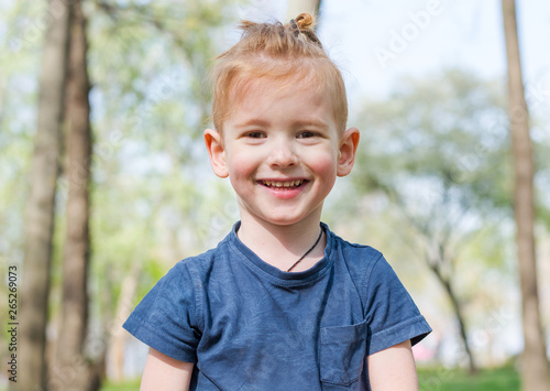 Portrait of a little boy who laughs in the park in spring