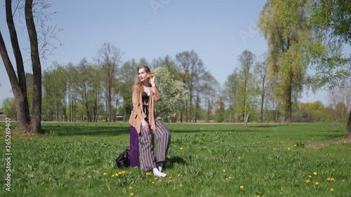 Young happy traveler arrived to new destination country - Waiting for her bus taxi - Emotions of a white caucasian female woman with light long hair wearng bra and beige jacket photo