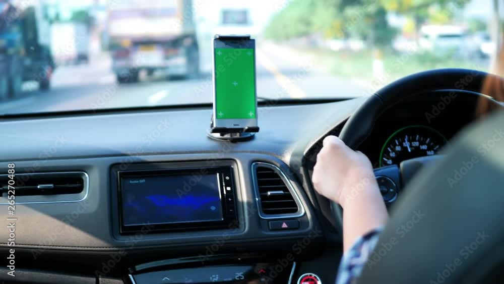 woman driving on the roads and the use of green-screen smart phone. See a map or listen to music. woman driving on the roads and the use of green-screen smart phone. See a map or listen to music.