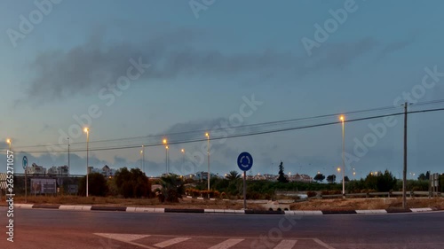 A camera panning in timelapse at a roundabout in Torrevieja at daybreak with the moon in the sky and street lighting. photo