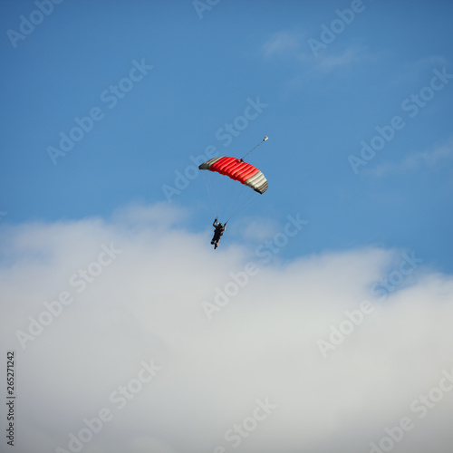 Bright parachute against a blue sky with clouds. Square image.