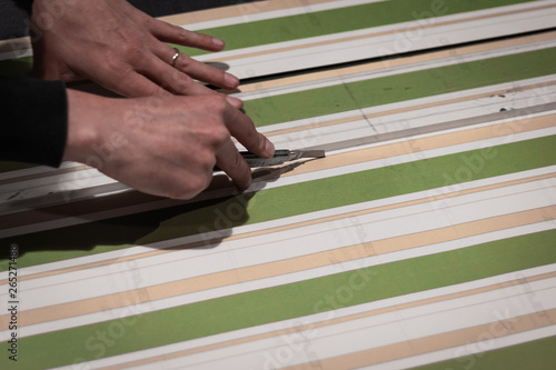 Rome, Italy.Print and fashion industry working together. Close up of a cobbler assembling a dress with black and colored printed fabrics. Cutting prcoess before stitching. Artisan and fashion concept.