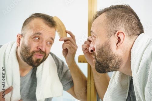 Man using comb in bathroom