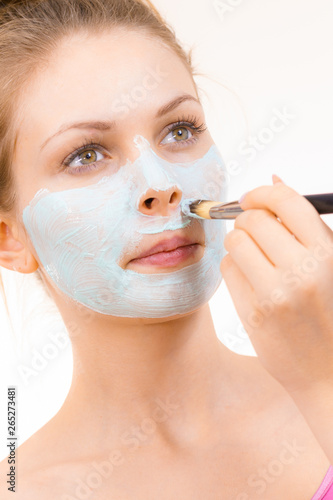 Girl apply green mud mask to face