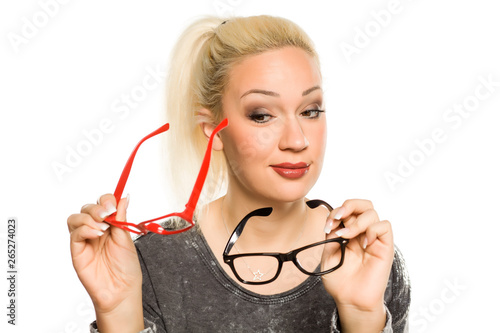 portrait of beautiful young blonde compare two pairs of glasses on white background photo