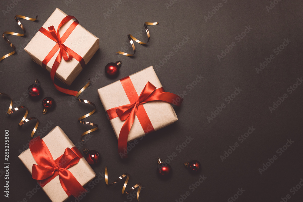 Christmas craft gifts with red ribbons and gold confetti on a dark contrast background