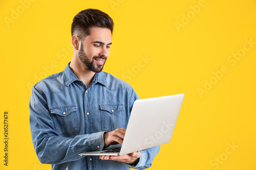 Male programmer with laptop on color background