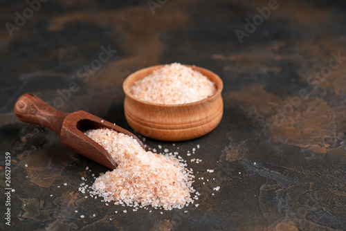 Pink himalayan salt in wooden bowl on black background