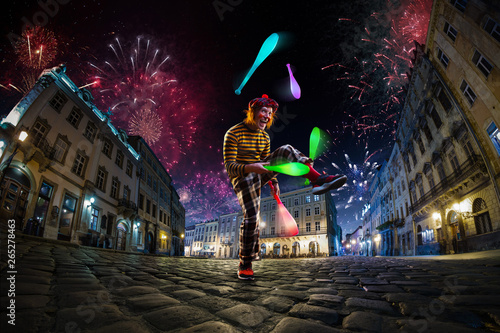 Night street circus performance whit clown, juggler. Festival city background. fireworks and Celebration atmosphere. © Anna Stakhiv