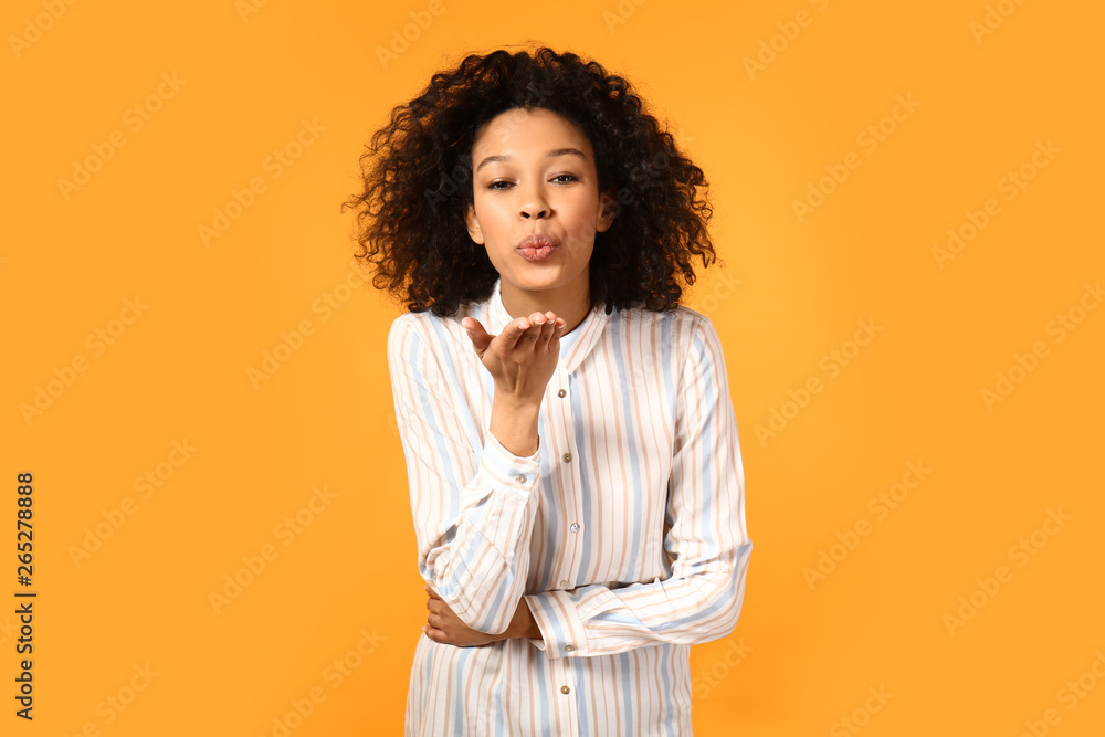 Young African-American woman blowing kiss on color background Young African-American woman blowing kiss on color background
