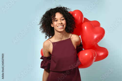 Happy African-American woman with air balloons on color background © Pixel-Shot