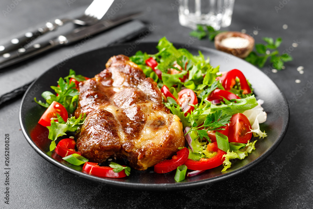 Baked pork steak with fresh vegetable salad on a plate