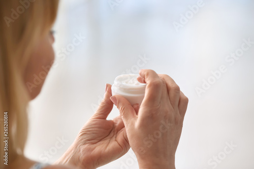Mature woman with jar of cream at home