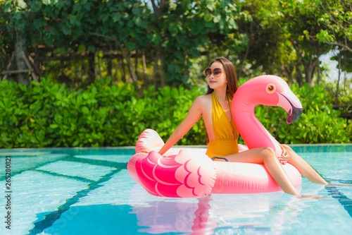 Portrait beautiful young asian woman on the flamingo inflatable float in swimming pool at hotel resort © siraphol