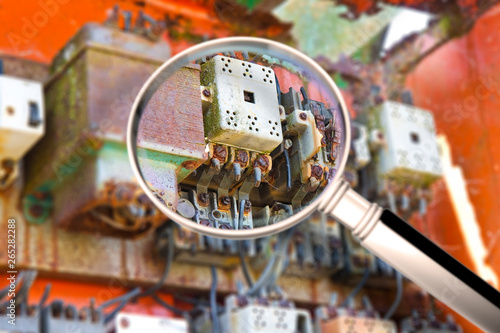 Old electrical control panel inside a damaged metal junction box - concept image seen through a magnifying glass © Francesco Scatena