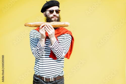 Portrait of a stylish man dressed in french style with striped shirt, hat and red scarf on the yellow background photo