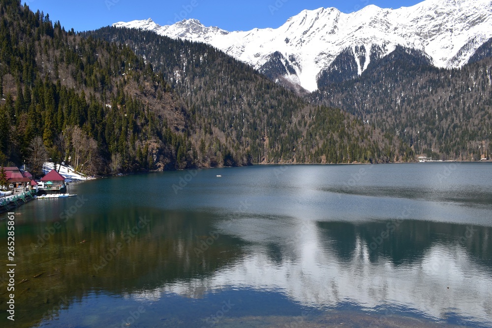 Lake with clear water among the high mountains with snowy peaks.