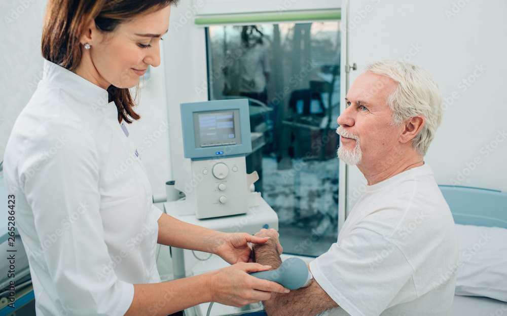 physiotherapist using ultrasound machine on hand of client in clinic. Physiotherapeutic treatment physiotherapist using ultrasound machine on hand of client in clinic. Physiotherapeutic treatment