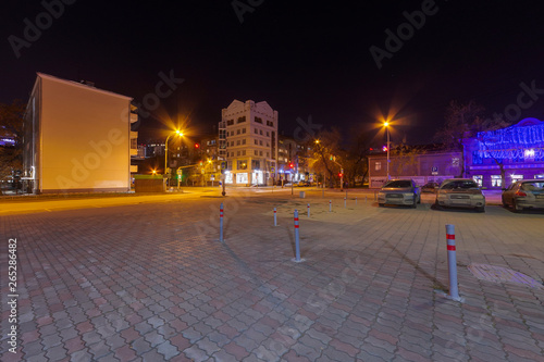 Night Ekaterinburg city without people, sidewalk with gray and pink paving slabs. Yellow and blue shades