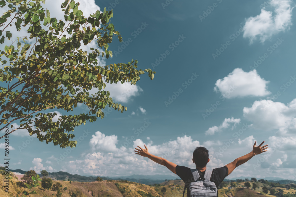 Backpacker man raise hand up on top of mountain with blue sky and white clouds abstract background. Backpacker man raise hand up on top of mountain with blue sky and white clouds abstract background.